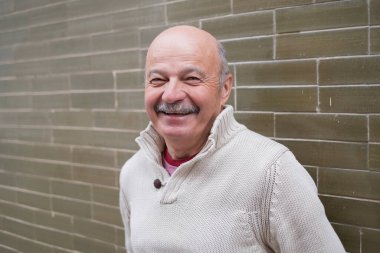 Duvarın yanında duran ve gülümseyen yaşlı İspanyol. Yüksek kalite fotoğraf