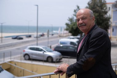 Portekiz 'de yürüyen ve okyanusa bakan yaşlı bir İspanyol. Ceket giyiyor ve bıyığı da var. Yüksek kalite fotoğraf