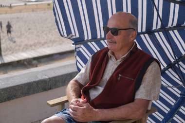 Yaşlı bir İspanyol, tatili boyunca Portekiz 'in küçük bir kasabasında güneş şemsiyesinin altında oturur. Yüksek kalite fotoğraf