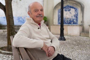 Yaşlı İspanyol adam ağaçların gölgesinde bir bankta oturuyor ve dinleniyor. Yüksek kalite fotoğraf