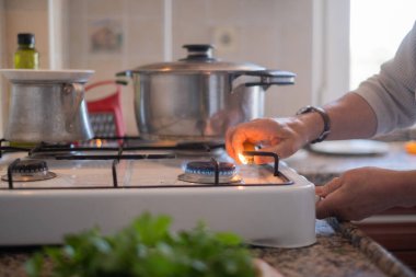 Mutfakta gaz ocağını açan yaşlı bir kadın var. Yüksek kalite fotoğraf