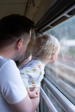 Genç adam babası, küçük çocuğuyla trenle geziyor, pencereye bakıyor.. 