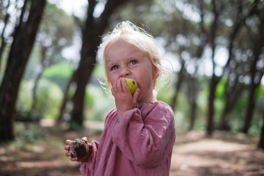 Ormanda armut yiyen şortlu sarışın Avrupalı kız. Yüksek kalite fotoğraf