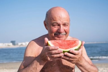 Yaşlı bir İspanyol sahilde karpuz yiyor. Yüksek kalite fotoğraf