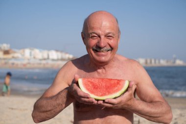 Yaşlı bir İspanyol sahilde karpuz yiyor. Yüksek kalite fotoğraf