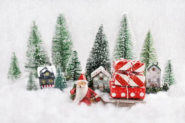 Vánoční Pozadí Figurkou Santa Claus Tahání Sáně Dárky Přes Vesnici — Stock fotografie