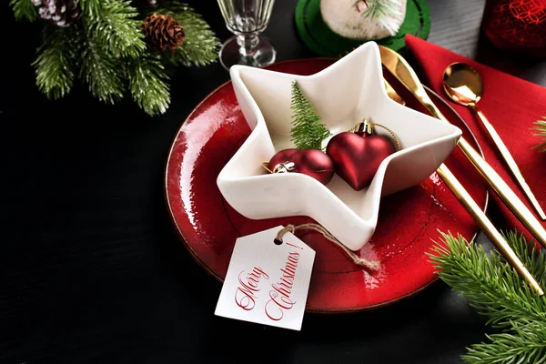 黒い表面に赤いプレートと白い星形のボウル カトラリーやモミの枝とクリスマステーブルの設定 — ストック写真