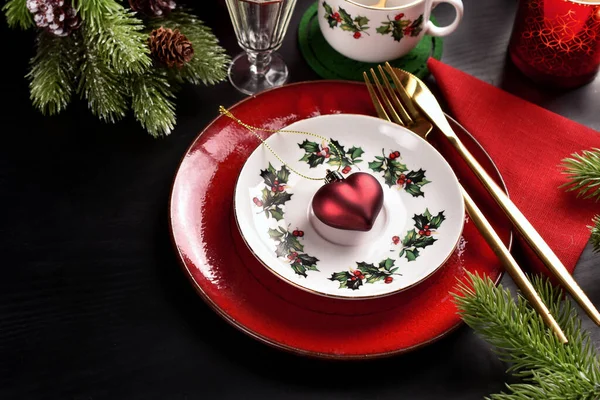 赤と白のプレートと黒の表面にカップ カトラリー キャンドルやモミの枝とクリスマステーブルの設定 — ストック写真