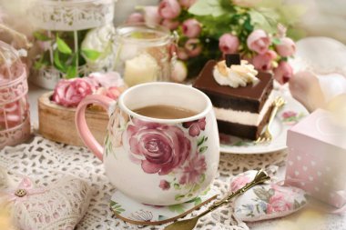 Romantic style coffee and chocolate cake on the table with flowers and love symbol decors