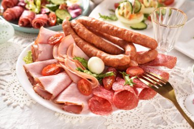 Easter table with a platter of sliced ham, salami and sausages for festive breakfast