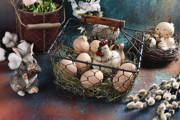 旧式复活节布置 有鸡蛋和一只装在铁丝篮子里的母鸡 一只兔子 一只鸟巢和一只猫 背景很肮脏 — 图库照片