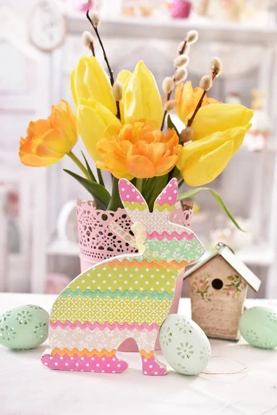 Ostertischdekoration Mit Buntem Hasendekor Eiern Und Einem Bund Gelber Tulpen — Stockfoto
