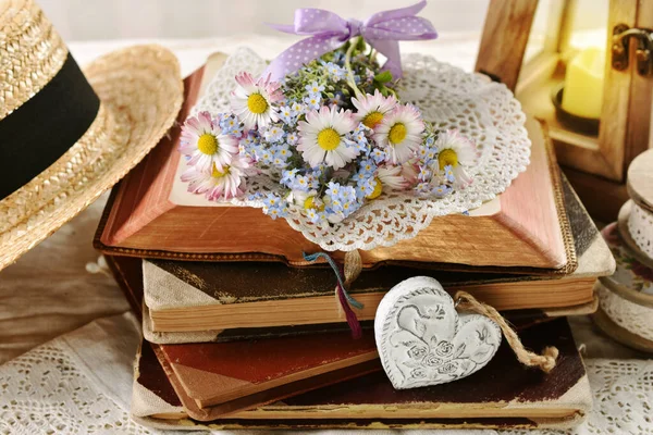 ヴィンテージスタイルのインテリアで開かれた古い本のスタックに横たわっているデイジーと忘れられない花の小さな束 — ストック写真