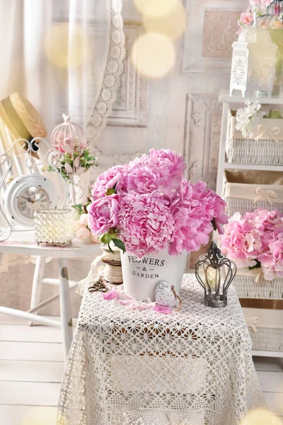 Shabby chic style interior with a bunch of fresh pink peonies on small coffee table with a lace tablecloth