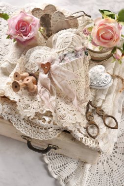 Beyaz ahşap çekmece, klasik dikiş malzemeleri, el yapımı tekstil kalp ve bağcık manzaralı. 