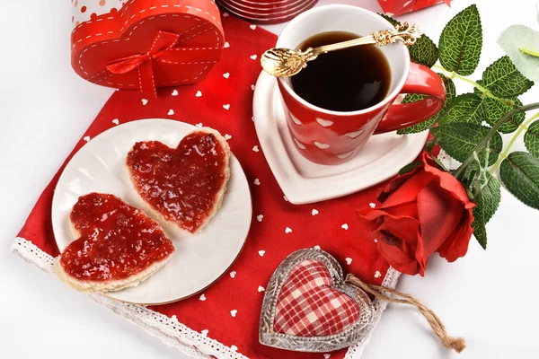 情人节的咖啡和心形烤面包 桌上放着覆盆子果酱和红餐巾 免版税图库图片