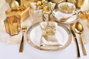 Zarif porselen sofra takımlarıyla beyaz ve altın renkli göz kamaştırıcı Noel masası 