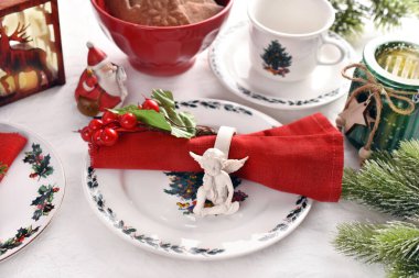 Beyaz, kırmızı ve yeşil renkli süslemeler ve sofra takımlarıyla şık bir Noel sofrası.