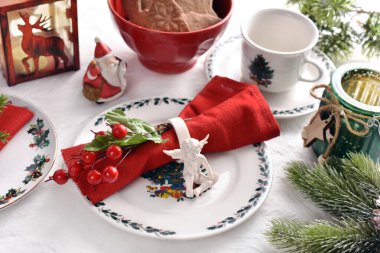 Beyaz, kırmızı ve yeşil renkli süslemeler ve sofra takımlarıyla şık bir Noel sofrası.