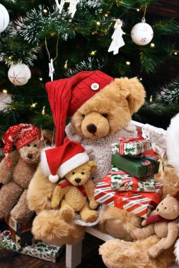 Noel Baba 'nın şapkalı oyuncak ayılar Noel zamanı Noel Baba' nın kürsüsündeki hediye kutularıyla oturuyorlar.