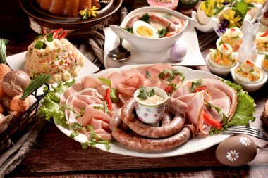 Bir tabak sosis, baharatlı yumurta ve ahşap masada geleneksel sebze salatasıyla Paskalya kahvaltısı. 