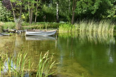 Güneşli bir günde gölün kenarında beyaz, klasik bir tekne.