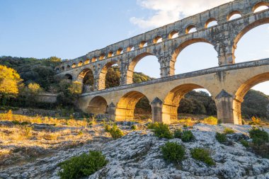 Güneş batarken muhteşem Pont du Gard. Antik Roma su kemeri köprüsü. MS 1. yüzyılda Roma 'nın Nemausus (Nimes) kolonisine su taşımak için inşa edilmiştir. Fotoğraf: Vers-Pont-du-Gard, Provence, Güney Fransa.