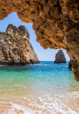 Portekiz 'in Algarve bölgesindeki Portimao yakınlarında kayaların içinden küçük, ilahi ve ulaşılması zor plaja dikey olarak fotoğraflandı.