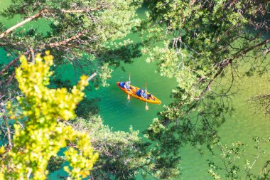 Canyon of the Tarn river, Occitanie, France - June 30 2016: Orange canoe-kayak through the trees in the gorges du Tarn clipart