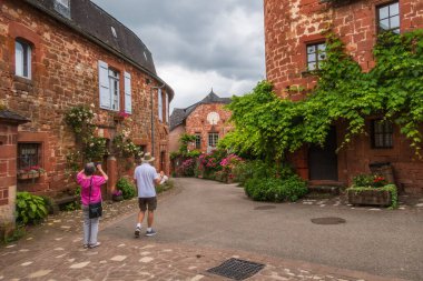 Collonges-la-Rouge, Fransa - 19 Haziran 2024: Fransa 'da Collonges-la-Rouge' da sokakta görülen turistler ve kırmızı evler, Correze