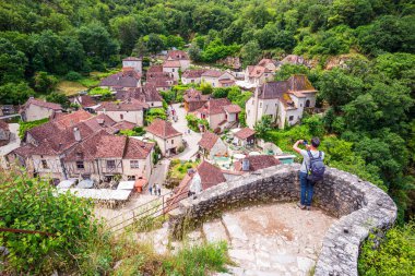 Saint-Cirq-Lapopie, Fransa - 15 Haziran 2024: Fransa 'nın güneybatısındaki Occitanie' de Saint-Cirq-Lapopie 'nin eski uçurum kenarındaki köyünü fotoğraflayan turist - Fotoğraf: WillyMobilo