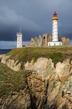 Saint-Mathieu de Fine-Terre Manastırı 'nın harabeleri ve kayaya bakan deniz feneri, Finistere, Brittany, Fransa