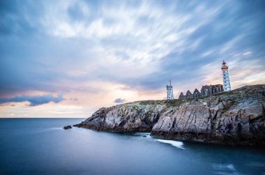 Saint-Mathieu de Fine-Terre manastırının kalıntıları ve gün batımında deniz feneri, Finistere, Brittany, Fransa