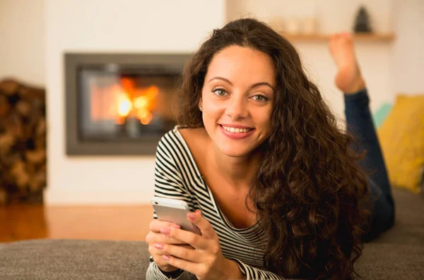 Mooie Vrouw Met Behulp Van Een Mobiele Telefoon Thuis Warmte — Stockfoto