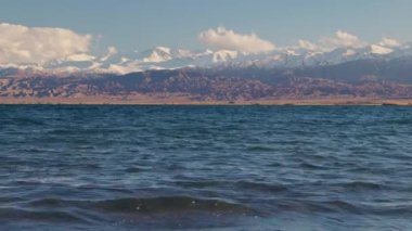 Blue calm water in Issyk-Kul lake with mountains on background at summer day, realtime footage.