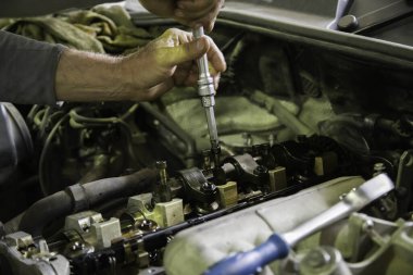 Tamircinin elleri vidaları söküyor ya da eski bir SUV 'de yanan motorun kollarını söküyor.