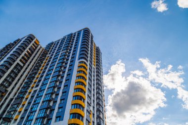 Mavi gökyüzü arka planında beyaz bulutlu, yeni inşa edilmiş apartmanlar..