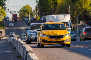 23 Mayıs 2022 'de Rusya, Tula' da yaz günü araba trafiği olan sarı bir taksi.