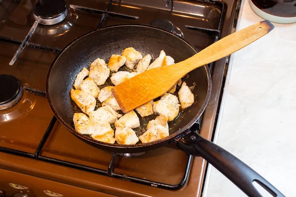 chicken breasts meat only on frying pan and wooden spatula, domestic healthy cuisine in real life situation.