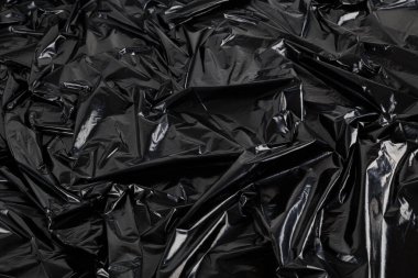 Buruşmuş siyah plastik film torbasının tam kare arkaplanı.