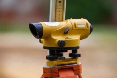 Üç ayaklı sarı bir teodolit ve bulanık bir arka planı olan bir cetvel. Jeodezi ölçüm kavramı.