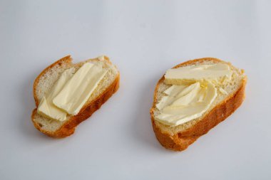 Beyaz arka planda tereyağlı iki parça beyaz ekmek..