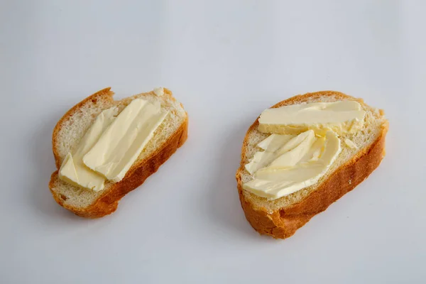 stock image two pieces of white bread with butter on white background.