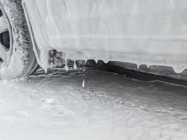 Oto yıkama sırasında beyaz arabadan su damlıyordu..