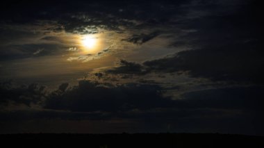 moon between night clouds above horizon at midnight clipart