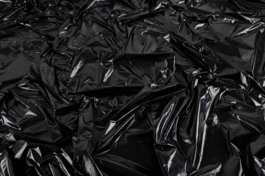 Buruşmuş siyah plastik film torbasının tam kare arkaplanı.