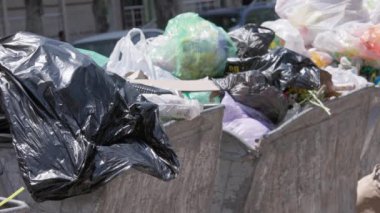 Büyük şehirde yaz günü, ağır çekimde aşırı dolu çöp bidonları..