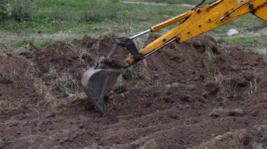 Kazı kovası kepçesi toprağın üst katmanını kaldırır ve onu yakınlaştırır..