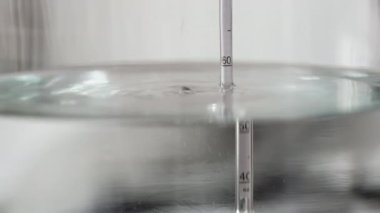 alkol damıtma işlemi yakın çekim - sıvı damıtılmış şeffaf sıvı içinde yüzen alkoholometre ile büyük cam kavanozda akıyor.
