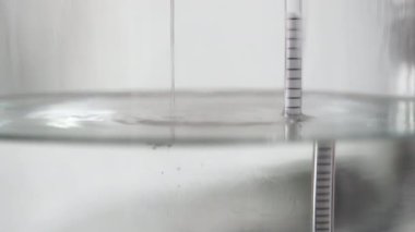 alkol damıtma işlemi yakın çekim - sıvı damıtılmış şeffaf sıvı içinde yüzen alkoholometre ile büyük cam kavanozda akıyor.